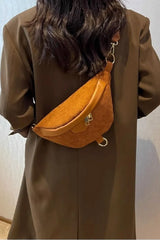 Person wearing a brown coat with an orange waist bag on a plain background