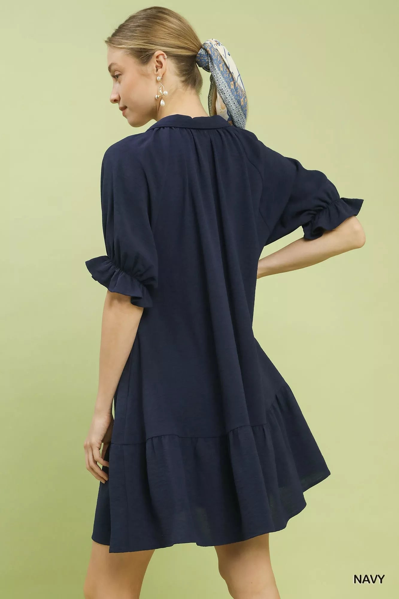 Woman wearing a navy dress on a light green background