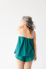 Woman wearing a green top and shorts set against a white background