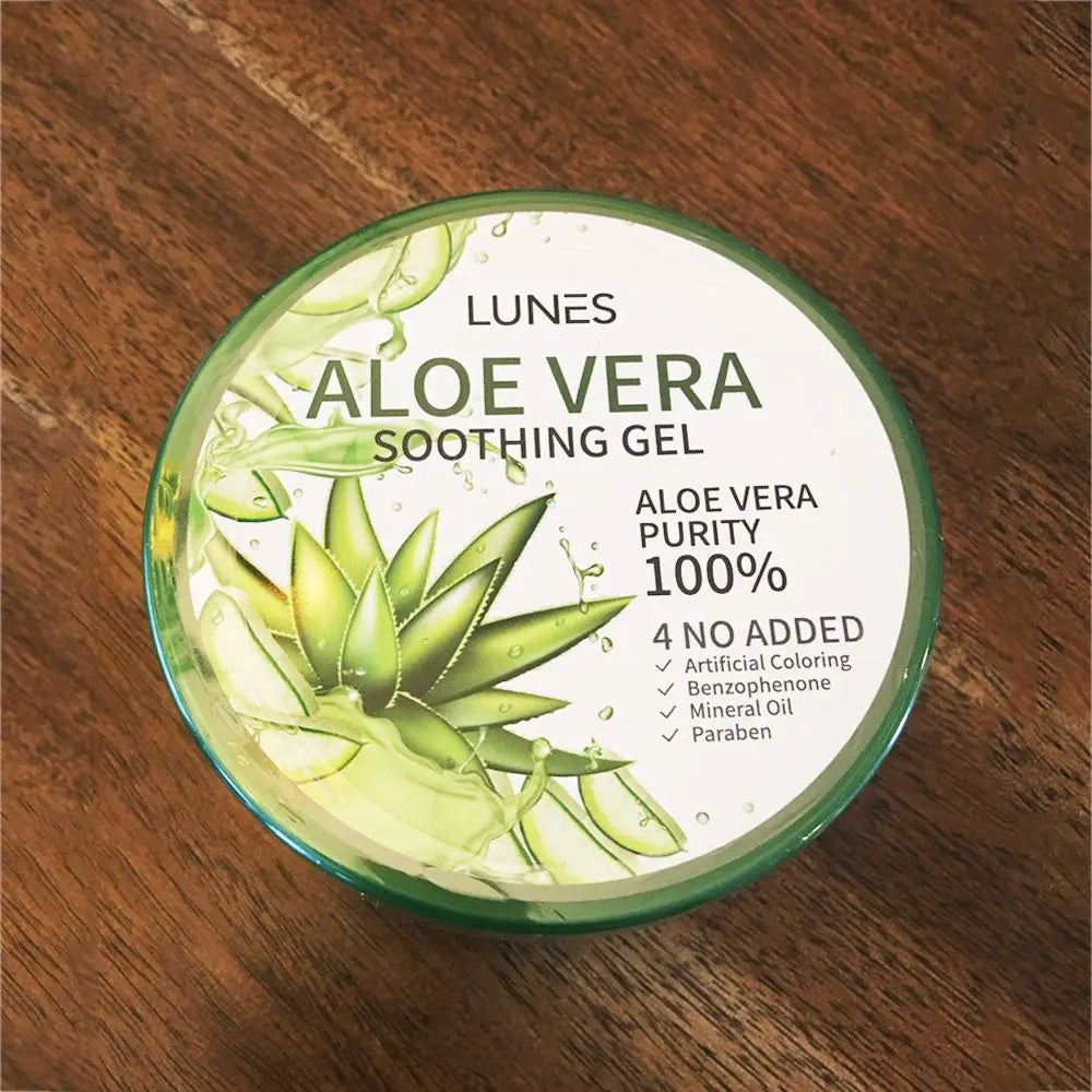 A jar of Aloe Vera soothing gel with a green lid, alongside slices of aloe vera and aloe leaves. The label on the jar indicates it is 100% pure Aloe Vera gel.