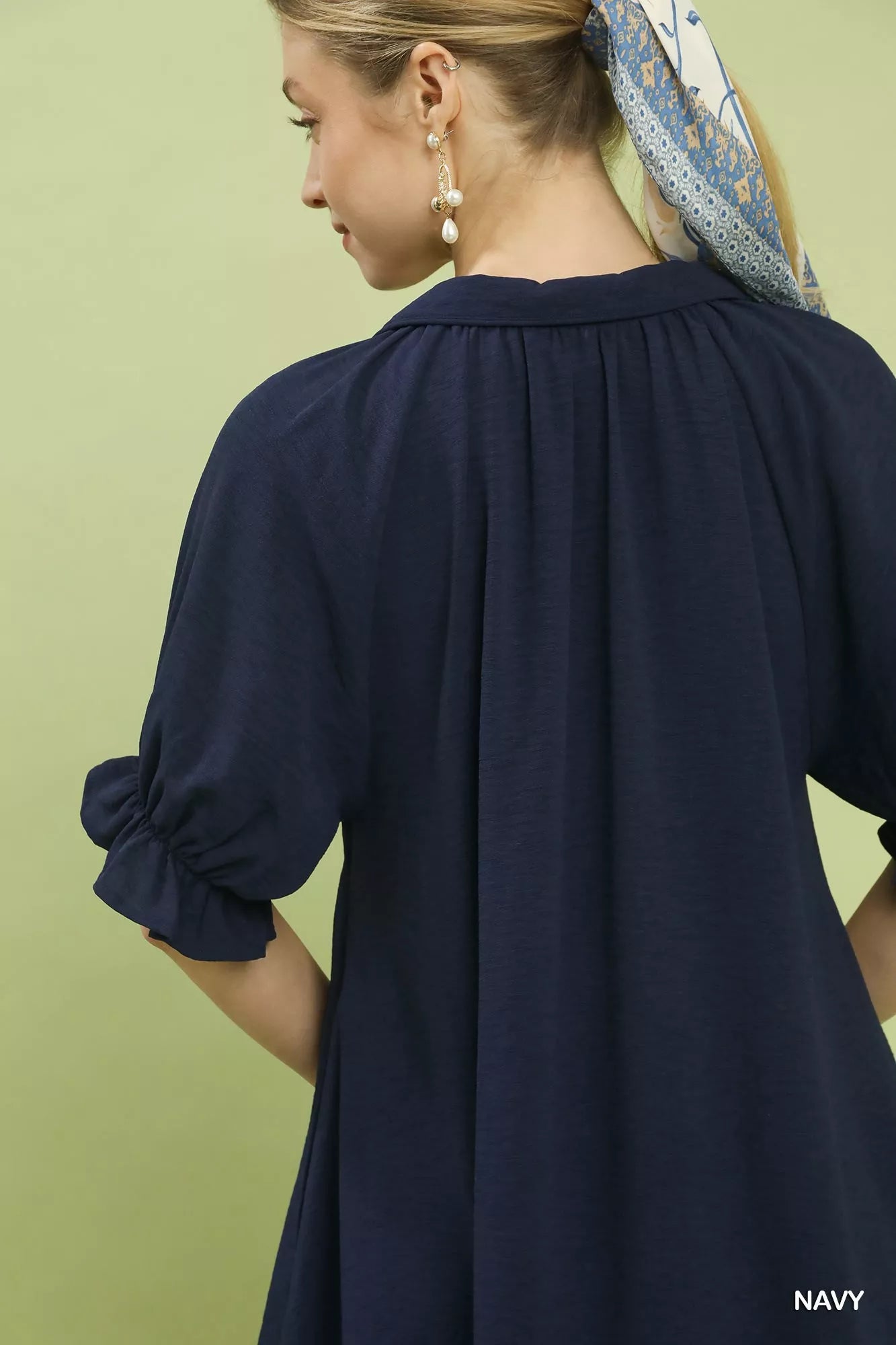Navy blue dress worn by a person with a green background