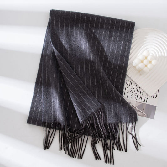 Black and gray striped scarf with fringes on a white surface