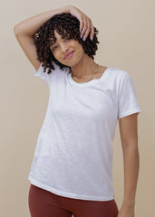 Woman wearing a white t-shirt and maroon pants against a beige background