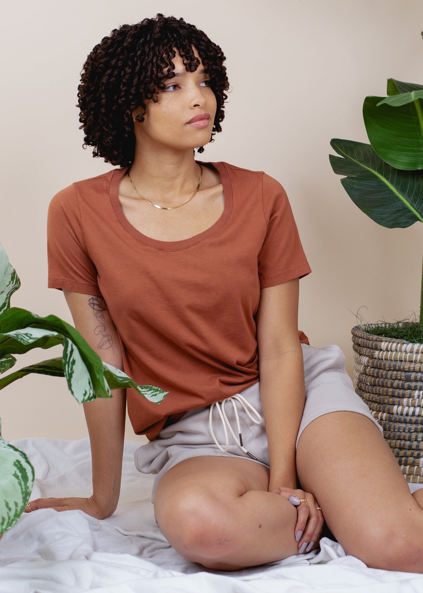 Woman sitting on a bed with plants around her