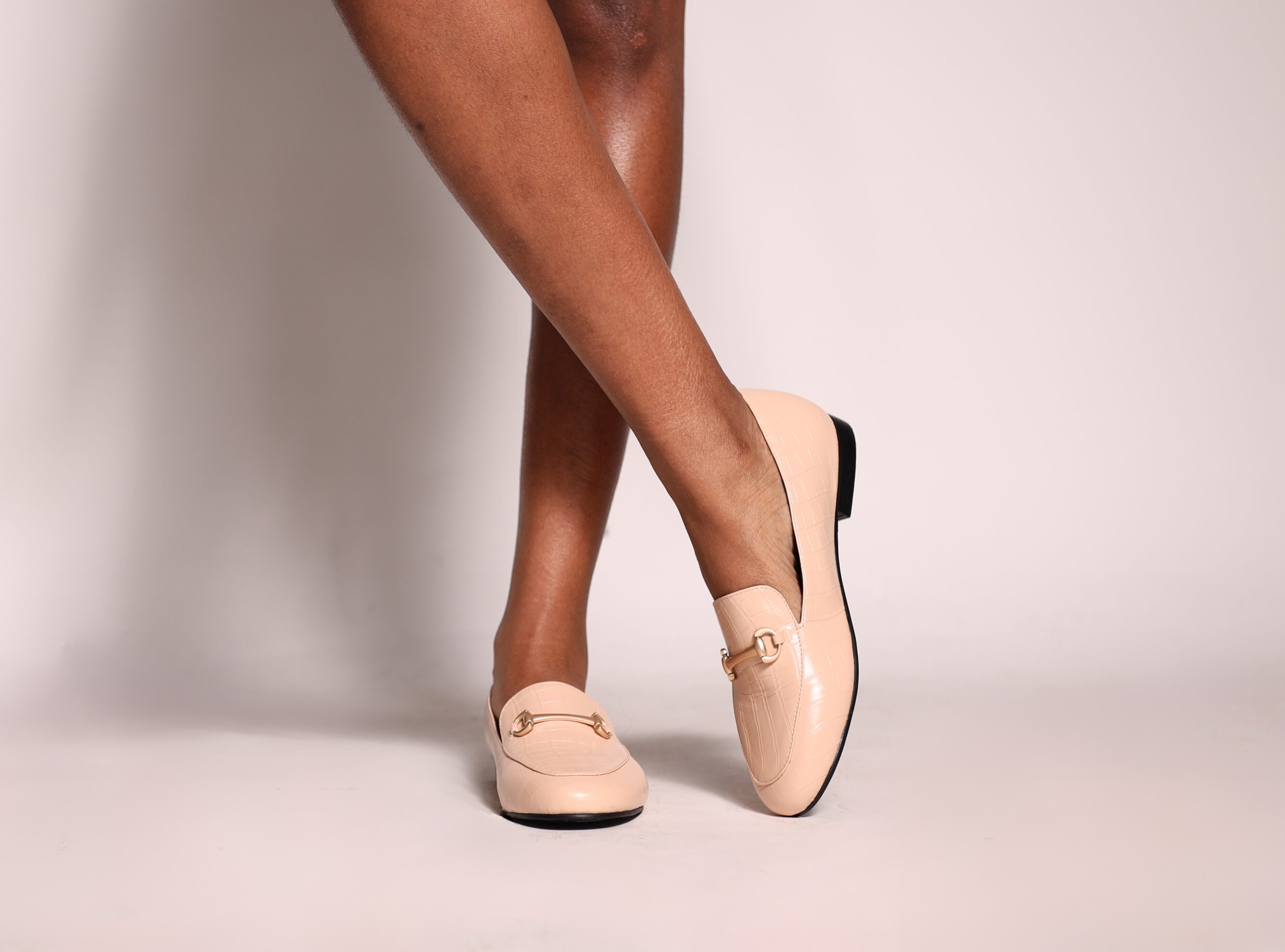 Beige loafers worn by a person on a plain background