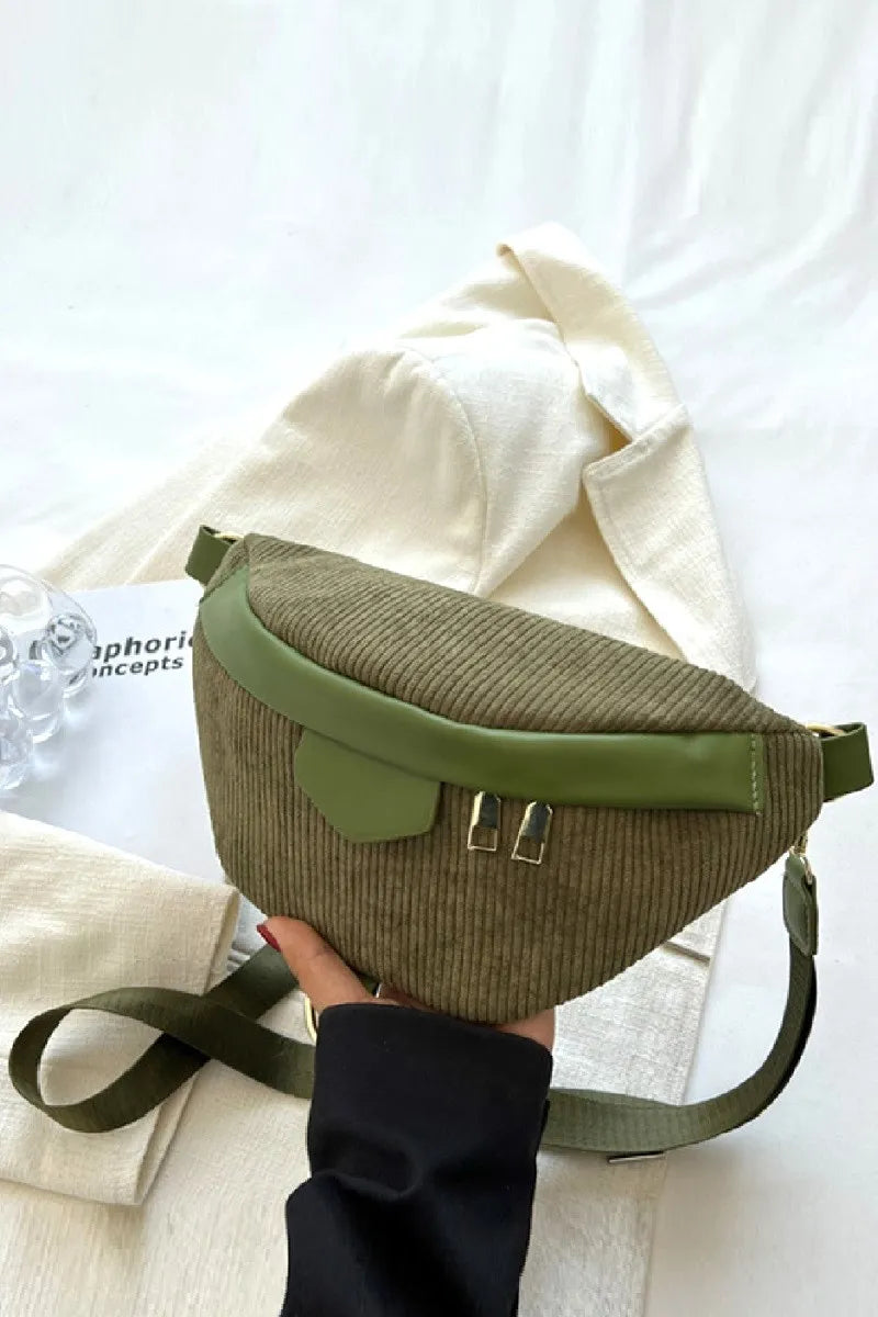 Green and brown waist bag held by a hand on a white background