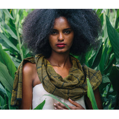 Woman with an afro wearing a green scarf in a lush green setting