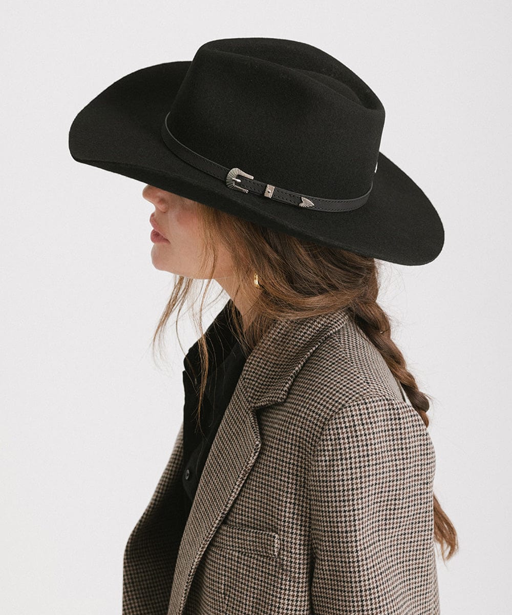 Person wearing a black cowboy hat and checkered coat on a white background