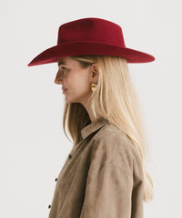 Woman wearing a red hat and beige coat on a white background
