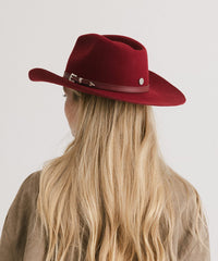 Red cowboy hat worn by a person with blonde hair on a plain background