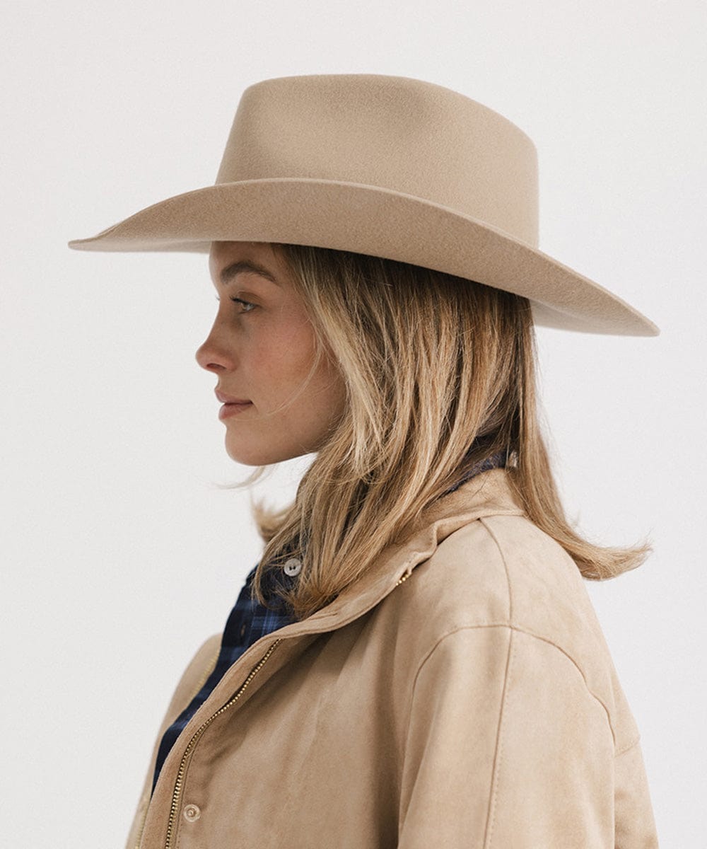 Woman wearing a beige hat and coat on a white background