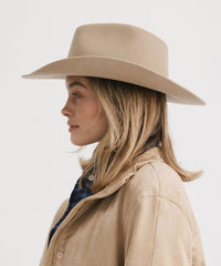 Woman wearing a beige hat and coat on a white background