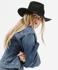 Person wearing a black hat and blue denim jacket on a white background
