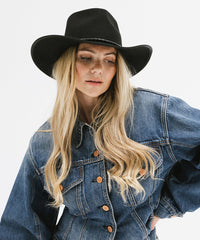 Woman wearing a black hat and denim jacket on a white background