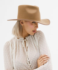 Woman wearing a beige hat and polka dot blouse on a white background