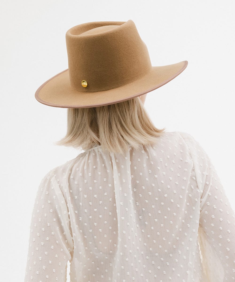 Person wearing a brown hat and white polka dot shirt on a light gray background