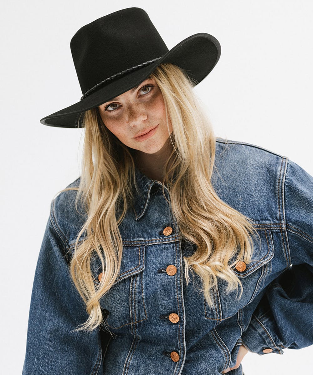 Woman wearing a black hat and blue denim jacket on a white background
