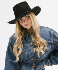 Woman wearing a black hat and blue denim jacket on a white background