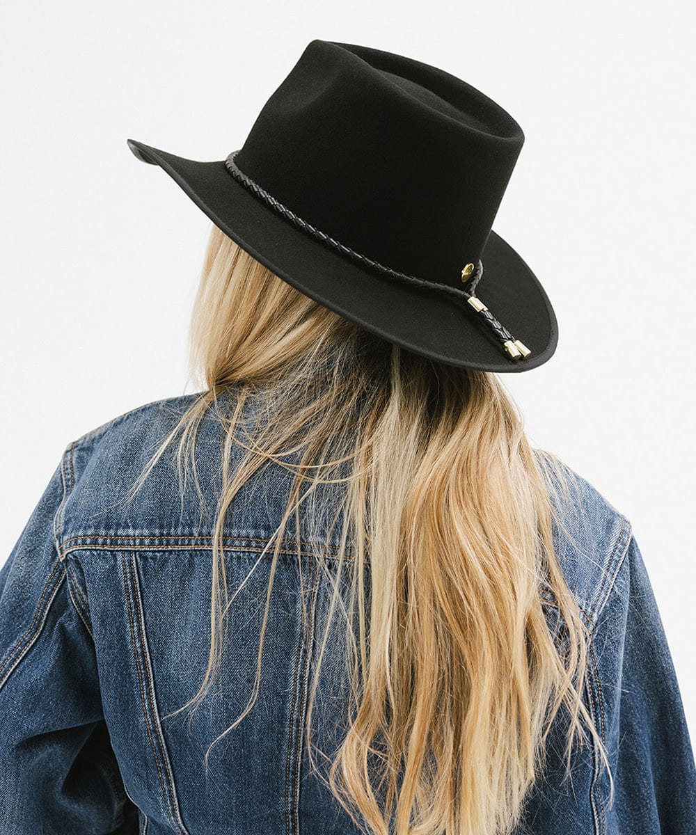 Person wearing a black hat and denim jacket on a white background