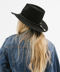 Person wearing a black hat and denim jacket on a white background