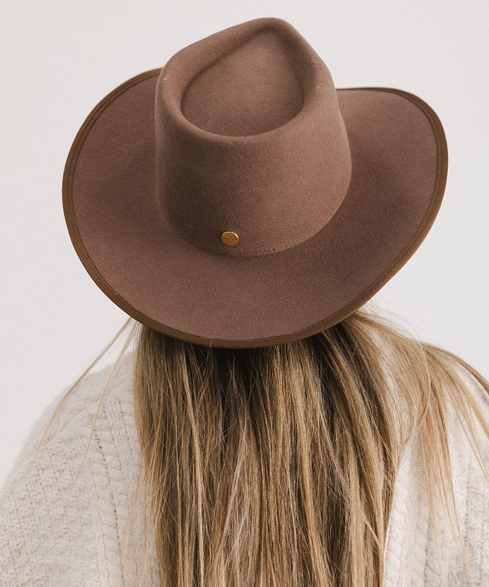 Brown cowboy hat worn by a person with blonde hair on a light gray background