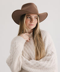 Woman wearing a brown hat and beige sweater on a white background