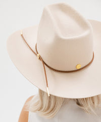 Beige cowboy hat with a brown leather strap on a light gray background