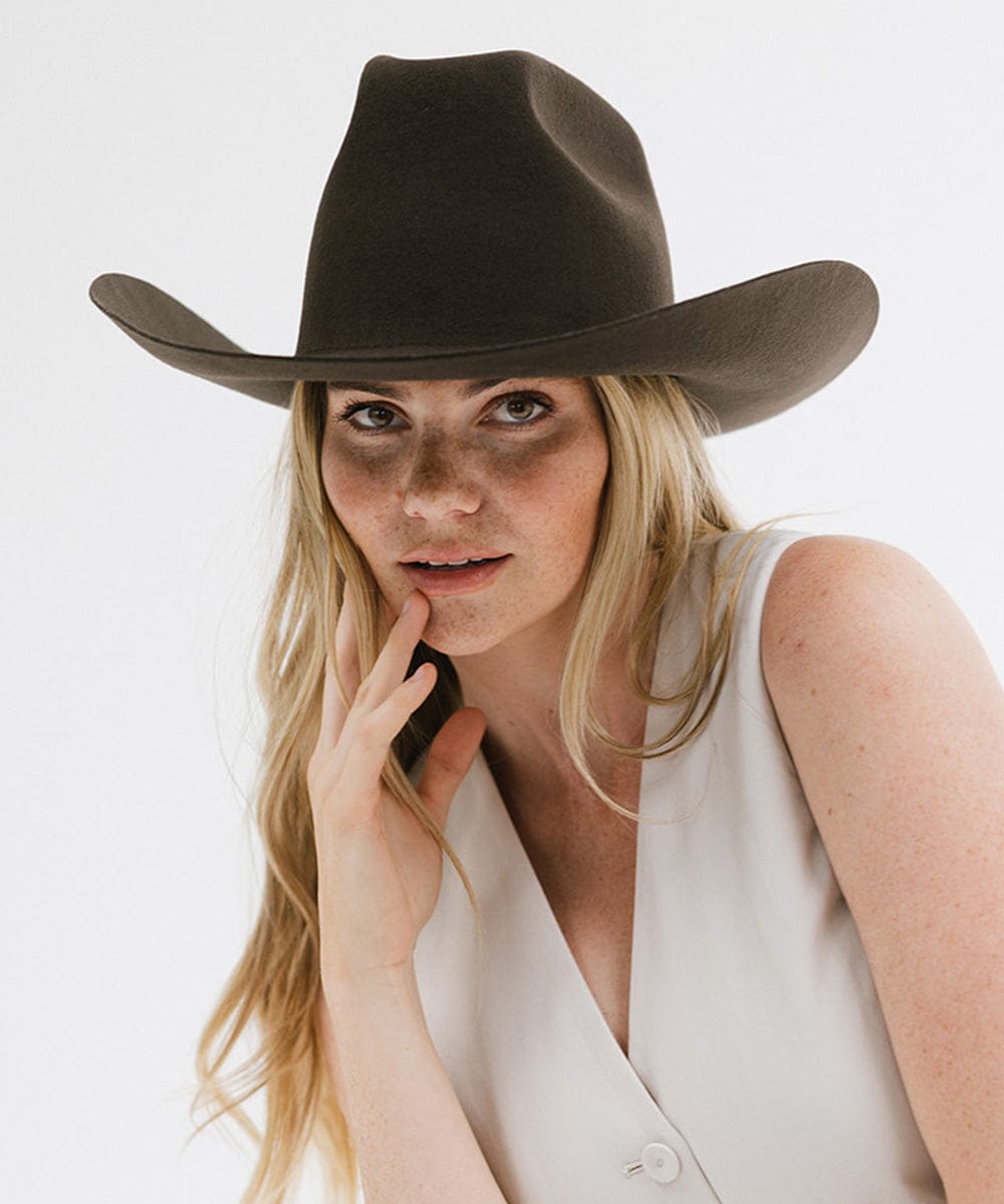 Woman wearing a brown cowboy hat against a white background