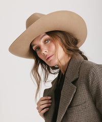Woman wearing a beige hat and checkered coat on a plain background