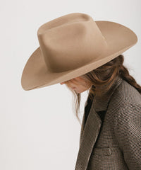 Person wearing a beige cowboy hat and plaid coat on a white background
