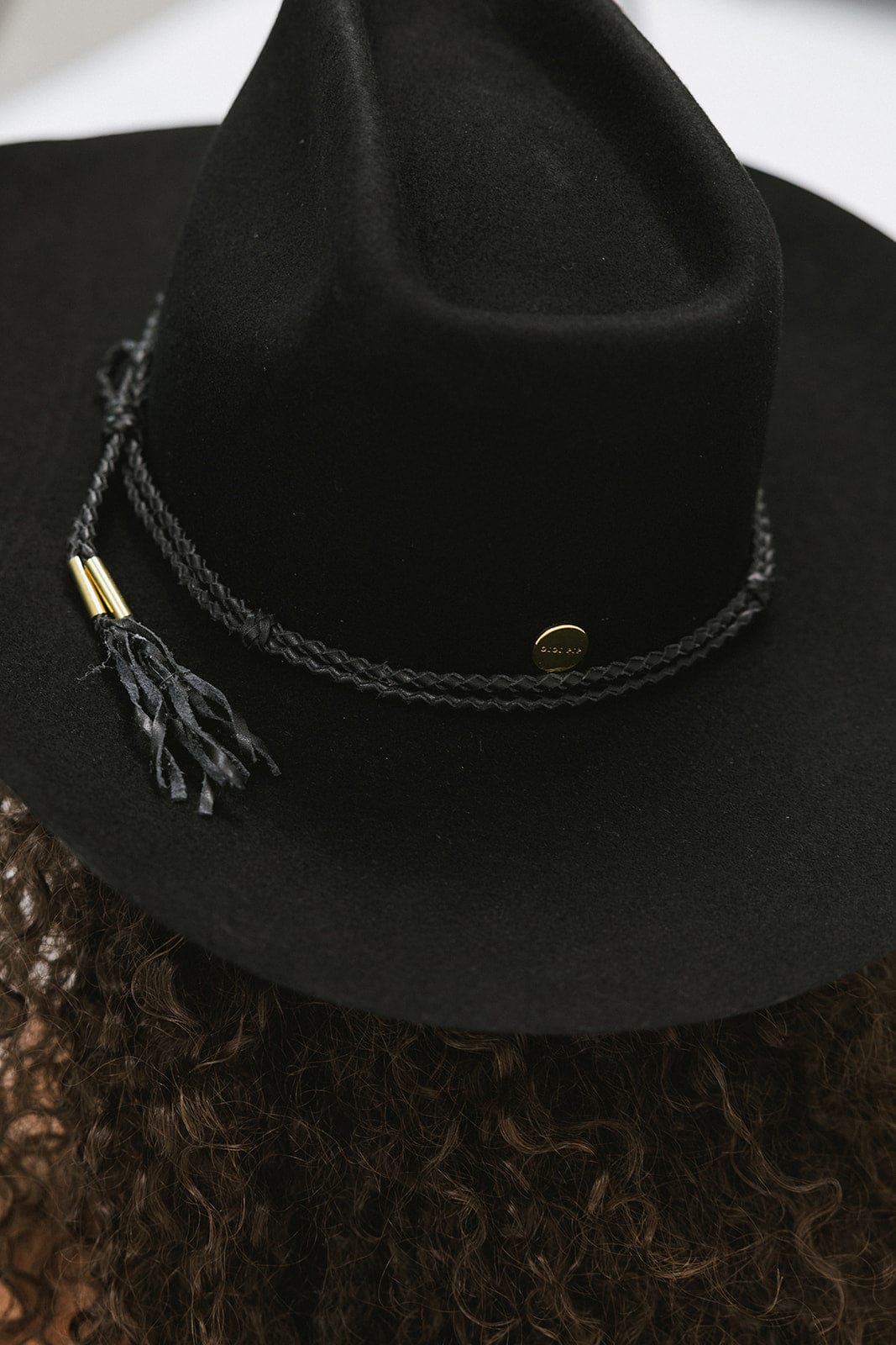 Black cowboy hat with a braided band and tassel on a textured surface
