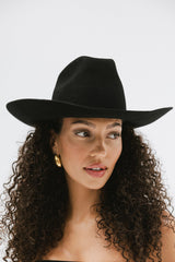 Woman wearing a black hat against a white background