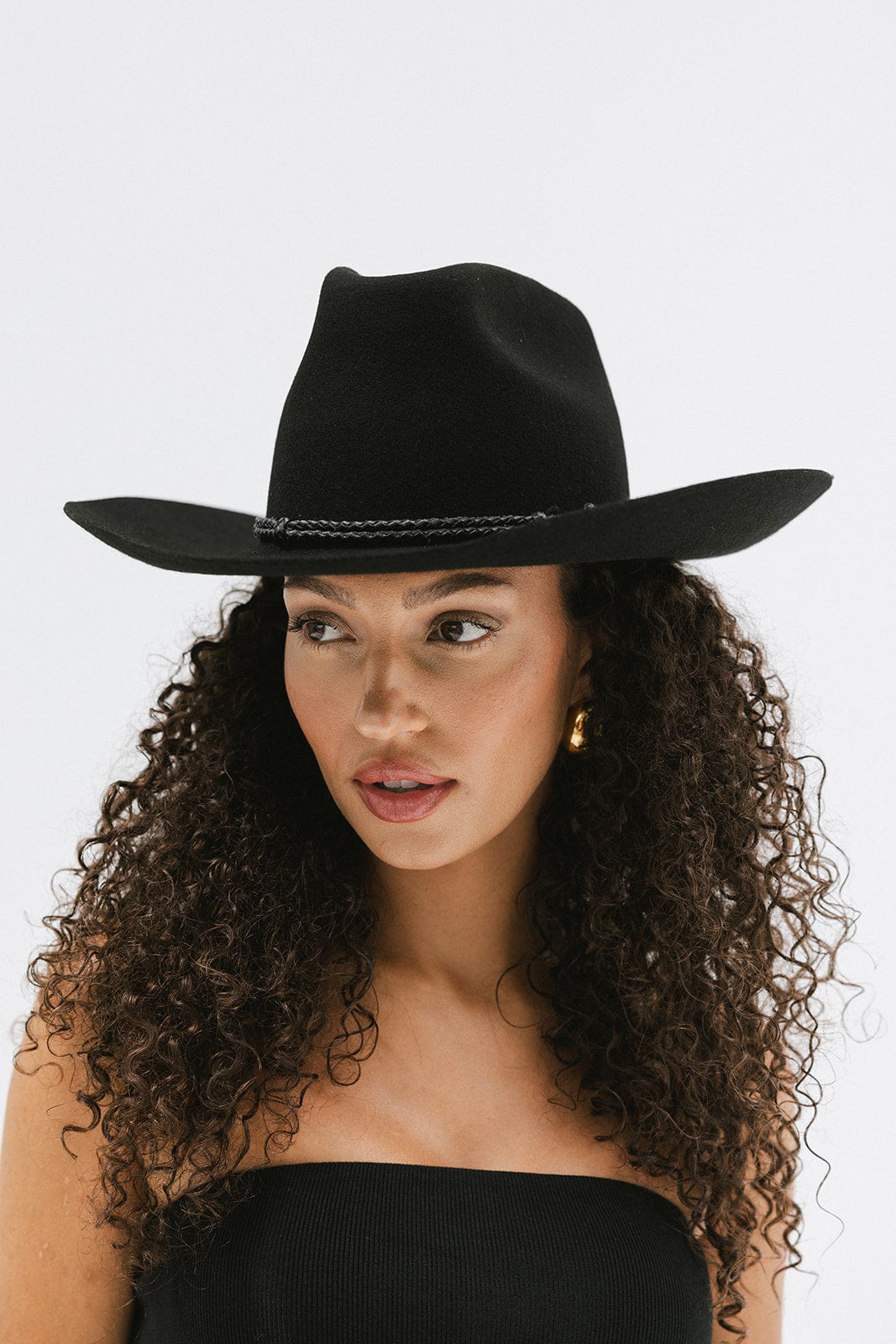 Woman wearing a black cowboy hat against a white background