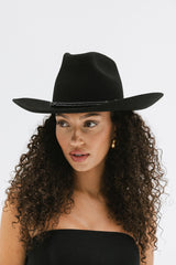Woman wearing a black cowboy hat against a white background