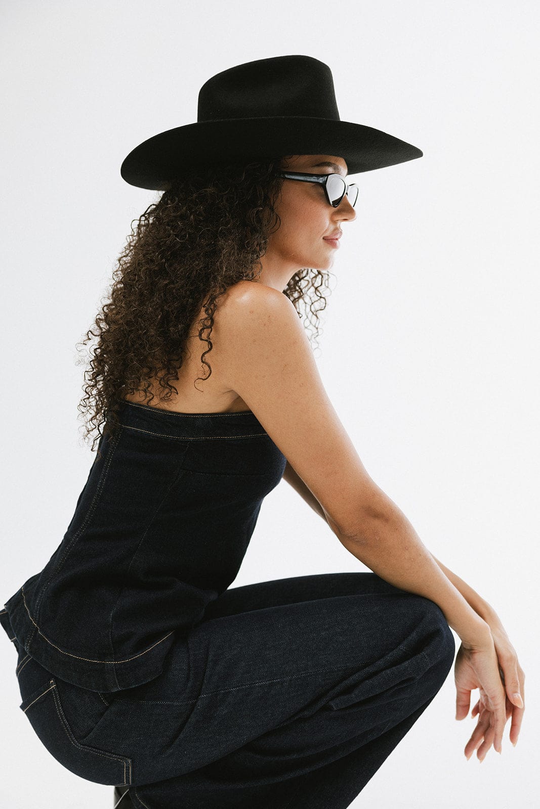 Woman wearing a black hat and sunglasses against a white background