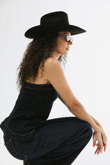Woman wearing a black hat and sunglasses against a white background