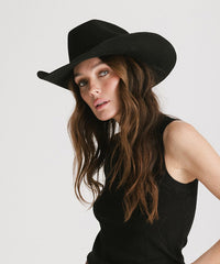 Woman wearing a black hat and black top against a white background