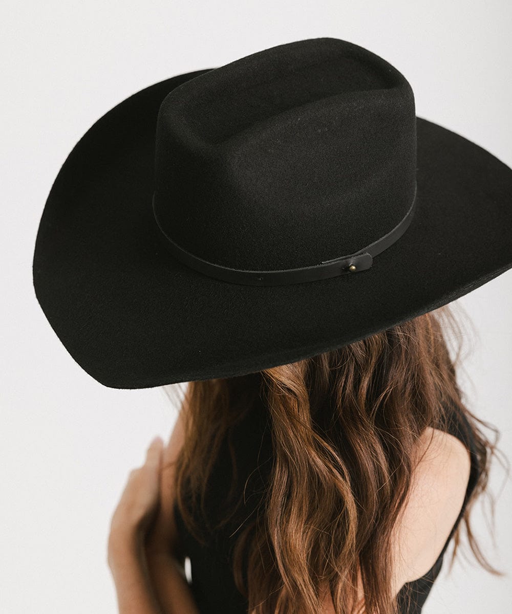 Black cowboy hat worn by a person with a blurred background