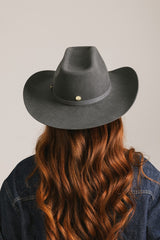 Person wearing a dark gray cowboy hat with a plain background