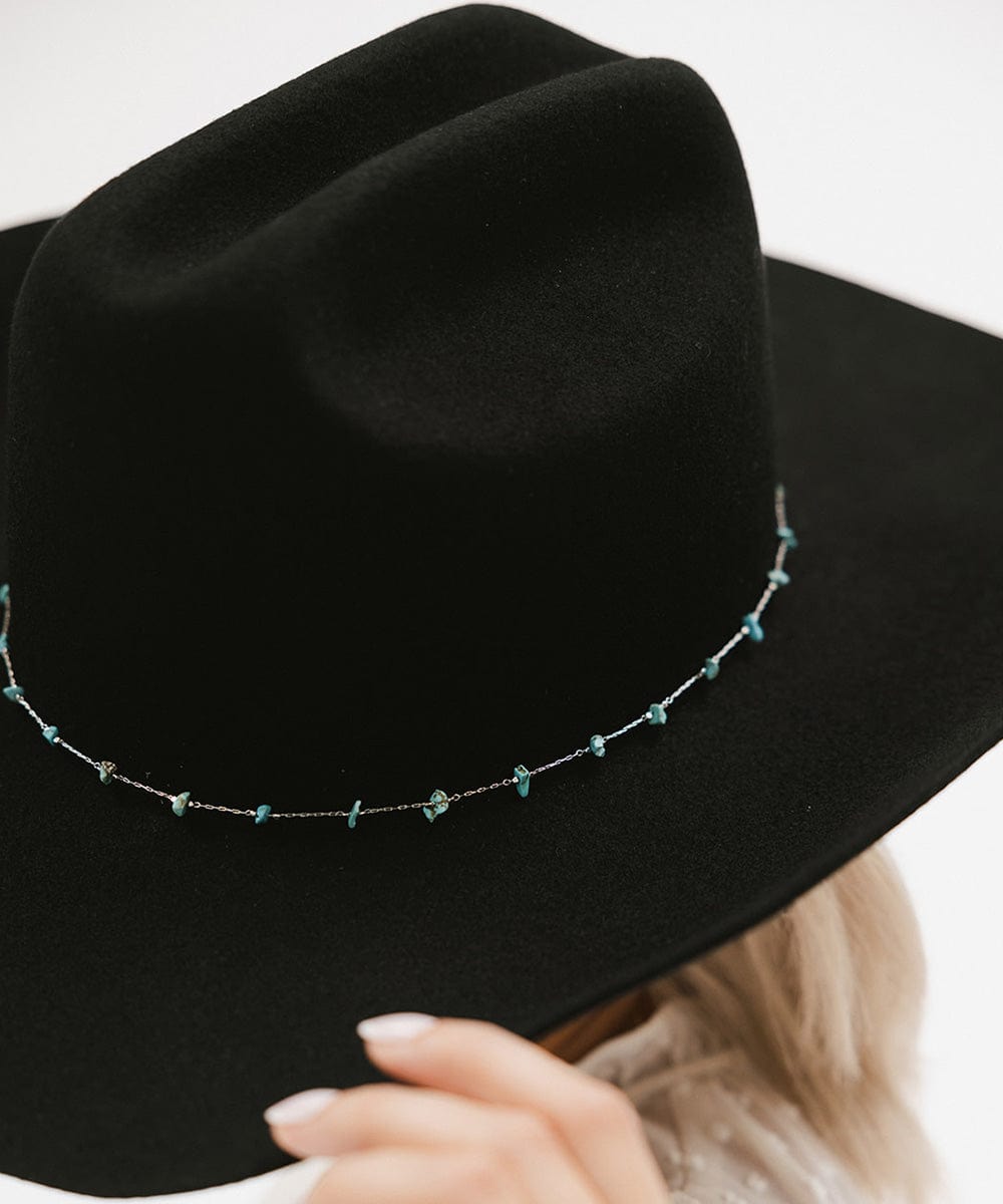 Black hat with decorative chain on a white background