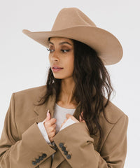 Woman wearing a beige hat and coat on a white background