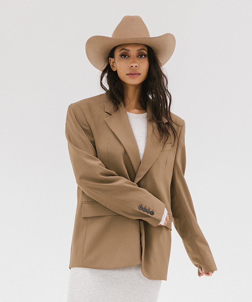 Woman wearing a beige blazer and hat on a white background