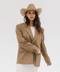 Woman wearing a beige blazer and hat on a white background
