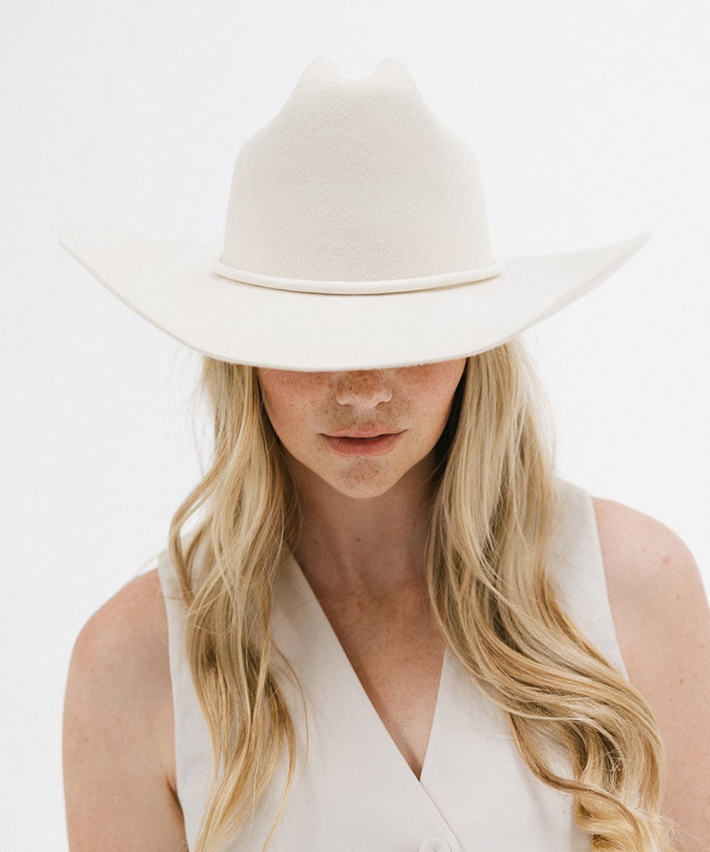 Person wearing a white hat and white top on a light background