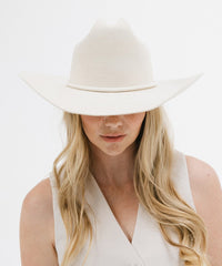 Person wearing a white hat and white top on a light background