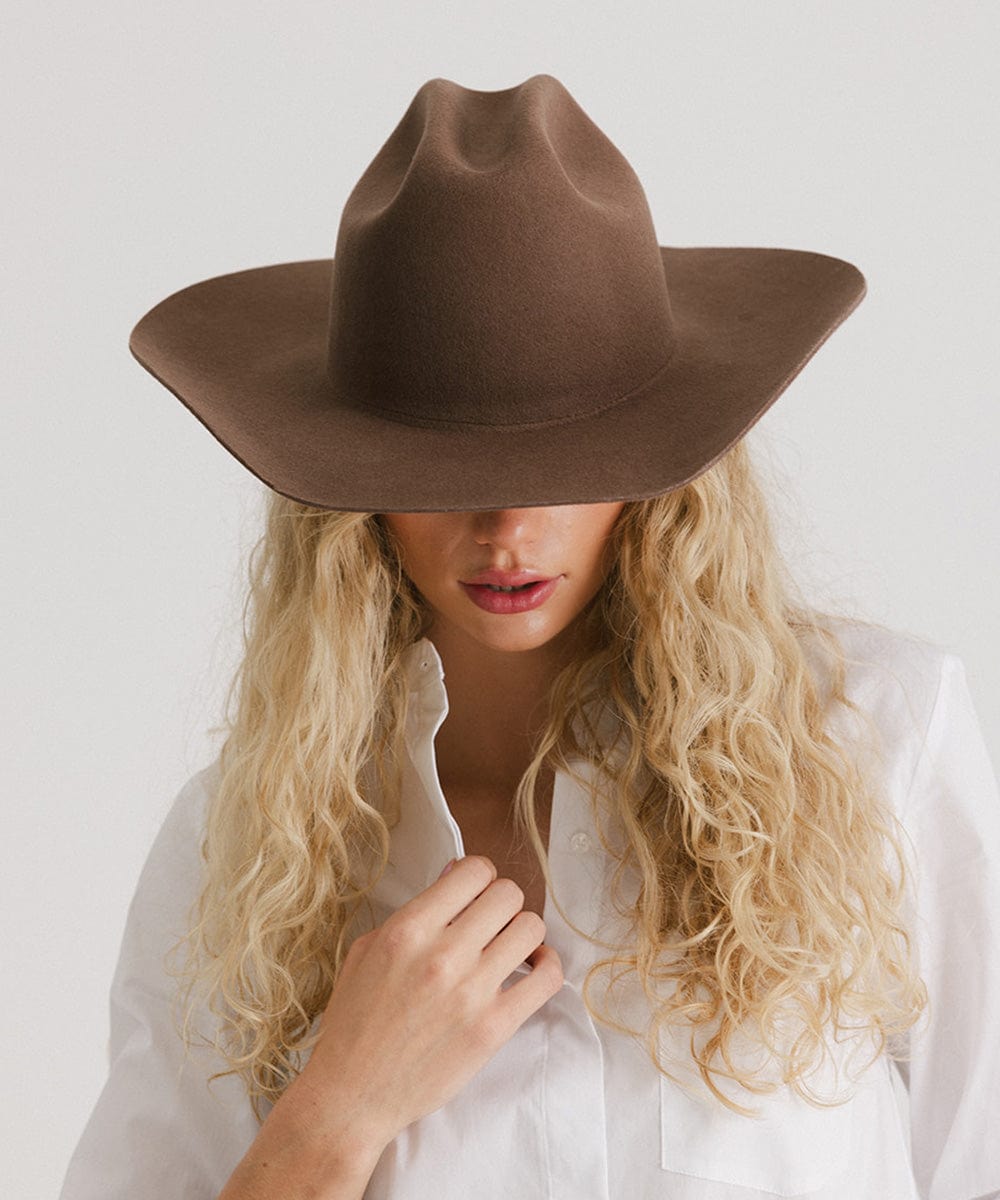 Person wearing a brown hat and white shirt against a plain background