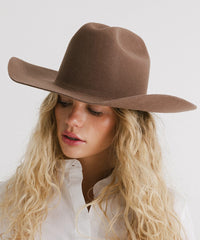 Woman wearing a brown wide-brimmed hat against a white background