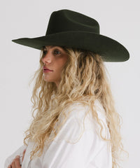 Woman wearing a dark green wide-brimmed hat against a white background