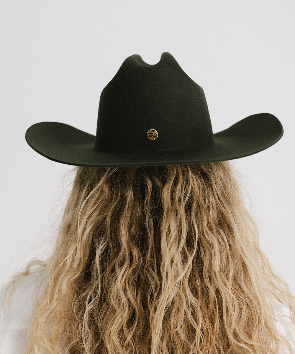 Black cowboy hat worn by a person with long blonde hair on a white background