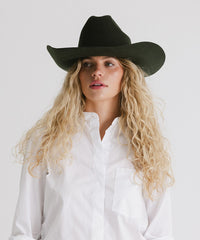 Woman wearing a black hat and white shirt against a plain background